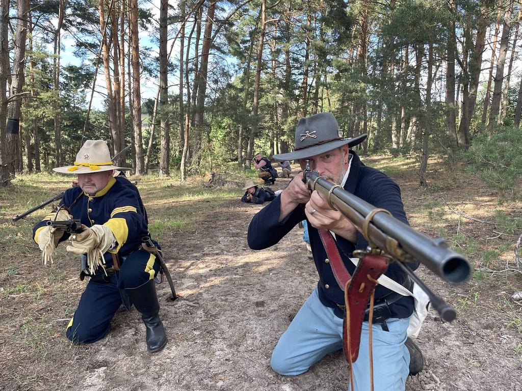 Historisches Western-Reenactment im Wald mit Cowboy-Hüten und Gewehren, Gruppen-Szene im Freien