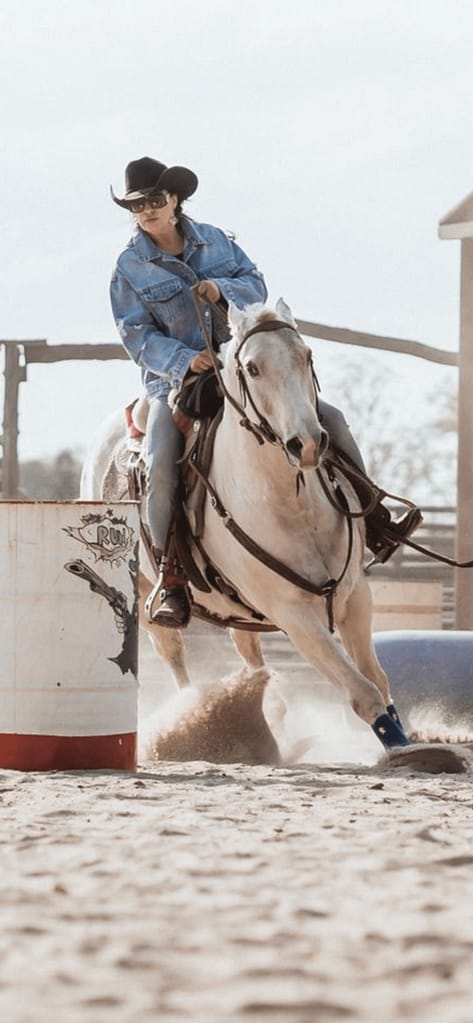 Western-Reiterin beim Barrel-Training im Roundpen, staubiger Sandboden, klassisches Ranch-Kurs-Setting